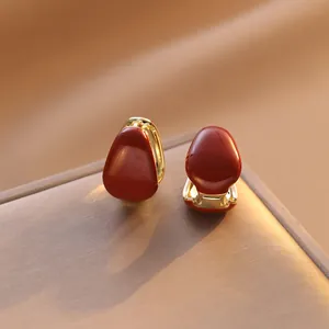 Macro shot of red enamel oval earrings with gold-plated base on a jewelry box