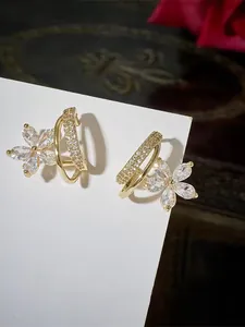 Dettaglio di orecchini a fiore con zirconi rosa e perle su cartoncino bianco