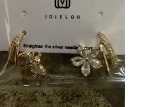 Dettaglio dell'orecchino a fiore dorato con cinque zirconi a goccia su espositore