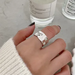 Nahaufnahme von silbernem breitem Ring mit unregelmäßigem Hammerschlagmuster am Finger
