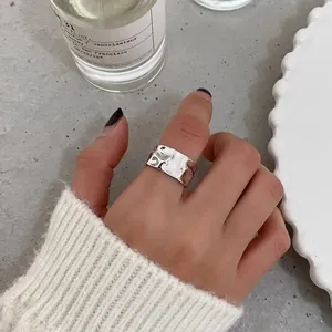 Brede zilveren ring met onregelmatige gehamerde textuur gedragen aan een hand