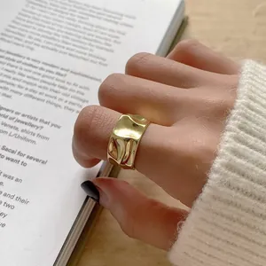 Brede gouden ring met onregelmatige gehamerde textuur gedragen door een model