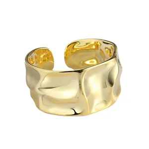 Brede open ring in goudkleur met onregelmatig gehamerd oppervlak en ribbel textuur