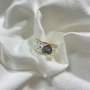 Dettaglio dell'anello in smalto bianco con cuore colorato e accenti di stelle dorate