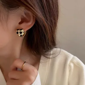 Close-up of heart-shaped checkerboard earrings with sparkling zircon and gold-plated trim
