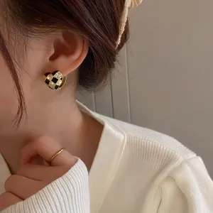 Close-up of heart-shaped checkerboard earrings with cubic zirconia on female model