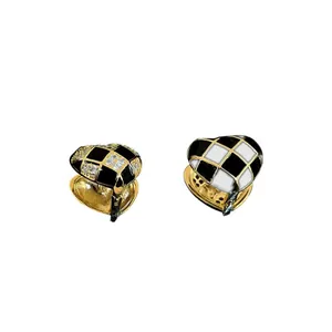 Macro view of checkered enamel heart earrings with zircon inlay and gold-plated finish