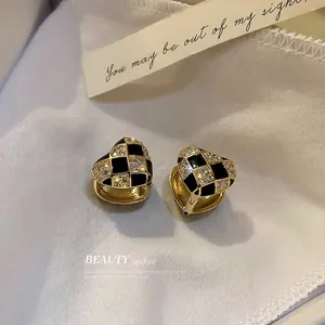 Elegant gold heart earrings with black enamel checkerboard pattern and zircon inlay