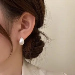 Detailed view of matte white teardrop stud earring with a minimalist bean-shaped design