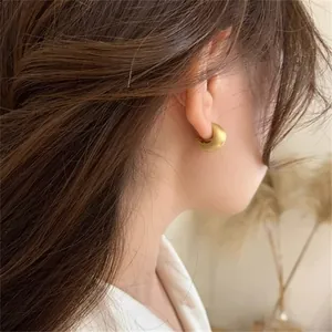 Close-up of vintage matte gold hoop earrings with brushed metal texture on a female model
