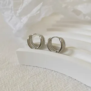 Dettaglio di orecchini a cerchio minimalisti argento a doppio strato a C su base bianca