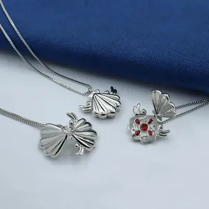 Anime-inspired silver shell locket necklace with red stones and wing details