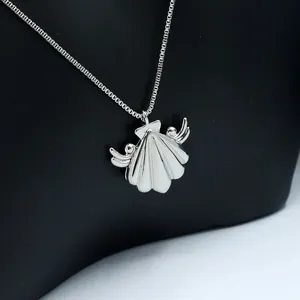 Macro view of a silver-toned shell pendant with angel wings on a polished box chain