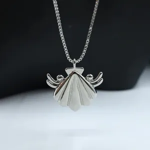 Close-up of a silver seashell pendant with wings on a box chain necklace