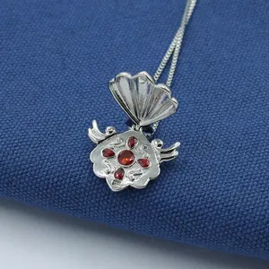 Macro shot of silver shell pendant with red gemstone inlays and intricate relief