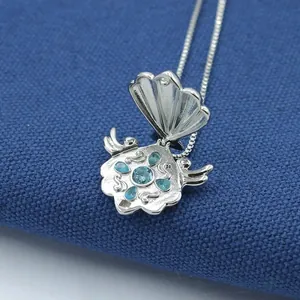 Detailed macro view of an open shell pendant necklace featuring sky blue gemstone inlays
