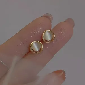 Elegante goldene S925 Silber Ohrstecker mit weißem Katzenaugenstein in der Hand