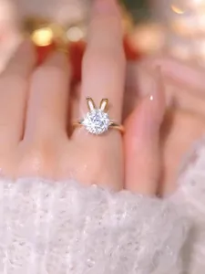 Detail of a golden rabbit ear ring with a sparkling round zircon on a white sweater background