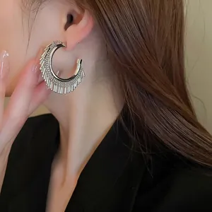 Dettaglio di orecchini a cerchio C in argento con strass scintillanti e nappe mobili