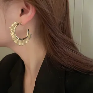 Primo piano di una modella con orecchini a cerchio dorati e dense nappe di frange in perline