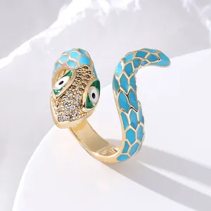 Macro shot of gold snake ring featuring blue enamel scales and sparkling zircon head