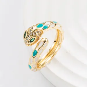 Detail of gold snake ring with teal enamel spots, green gem eyes and zircon accents