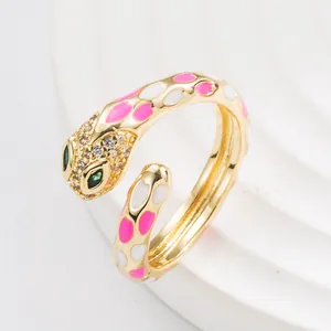 Punk style snake ring with pink and white enamel dots and green gem eyes in gold finish