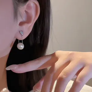 Orecchini a fiocco in argento con perla pendente e catena lunga su modella elegante