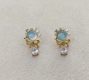 Detail of gold bow stud earring with blue cat eye stone, pearls and teardrop crystal
