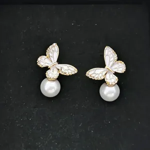 Macro detail of butterfly pearl earrings with gold frame and sparkling crystals