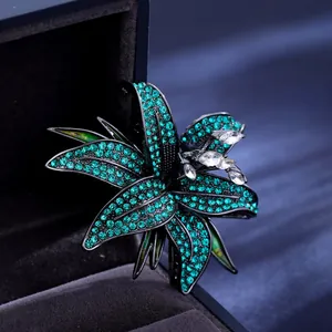 Elegant lily brooch with green rhinestones and crystals on black metal frame