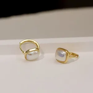 Elegant gold hoop earrings with square pearl inlay shown on a minimalist stand