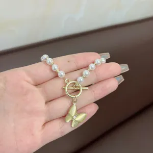 Detailed shot of white pearl necklace with golden butterfly pendant and OT clasp closure
