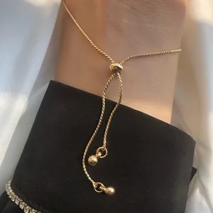 Detail of adjustable gold drawstring bracelet with small round beads and tennis chain