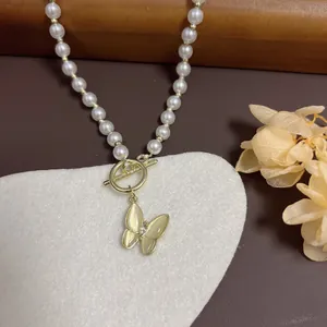 Elegant pearl necklace with butterfly pendant and gold OT buckle on heart mat