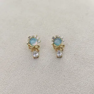 Elegant gold bow earrings with opal-style stone, pearls, and teardrop zircon drops