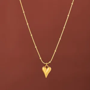 Close-up of gold-plated heart pendant with sleek snake chain and beaded details