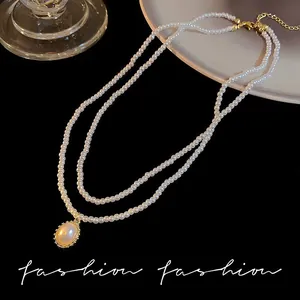Detail of a double-layered pearl necklace with a vintage golden oval pendant on black velvet