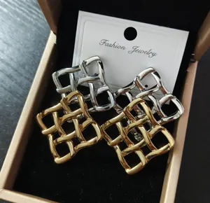 Dettaglio di orecchini a perno quadrati in maglia intrecciata oro e argento lucido