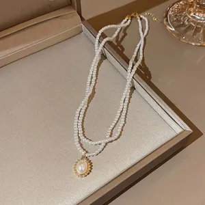 Close-up of double-layer camellia pearl necklace with gold oval pendant on satin