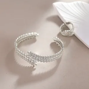 Detail view of silver feather-shaped bracelet and ring set with sparkling zircons