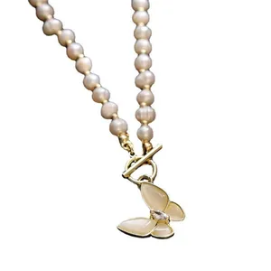 Close-up of pearl necklace featuring a golden OT clasp and yellow butterfly pendant