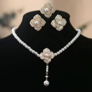 Detail view of pearl camellia necklace with white floral pendant on black neck bust
