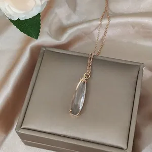 Detail view of a 16K gold teardrop pendant on silk fabric with a jewelry box