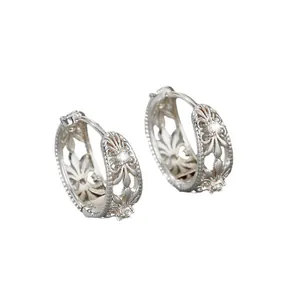 Detailed close-up of vintage hollow silver earrings with floral carvings and zircon