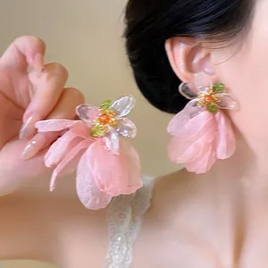 Pink chiffon flower earrings with resin center shown on model for a resort style look