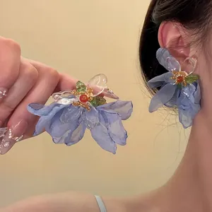 Close-up of blue fabric flower earrings featuring mesh petals and bead accents