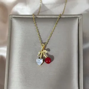 Elegante Kirsch-Halskette in Gold mit roter Perle und Herzkristall auf Satinstoff