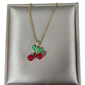 Elegant gold necklace featuring vibrant red cherry pendants and green enamel leaves