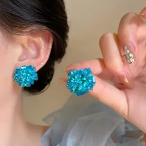 Macro detail of handmade hydrangea cluster earrings featuring blue crystal beads and silver needles